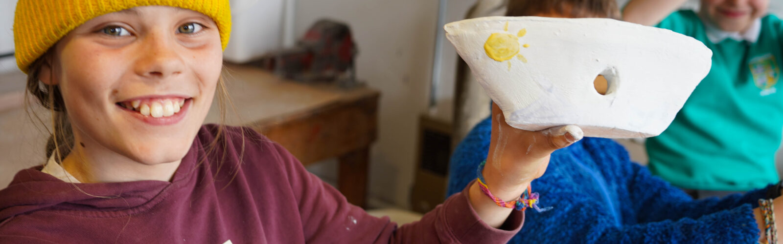 Artseen Tuesday. A child holding a bowl they made to camera