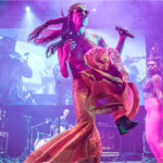 Newen Afrobeat perforers on a purple-lit stage.
