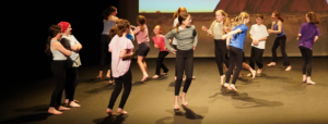 Summer Camp - children jumping and dancing on a stage.