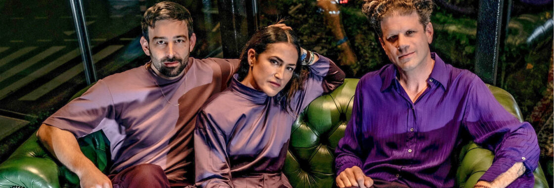 Joan As Police Woman dressed in purple looking at camera
