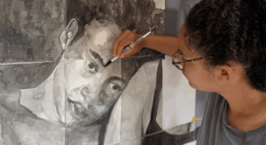 Woman concentrating on painting portrait in black ink